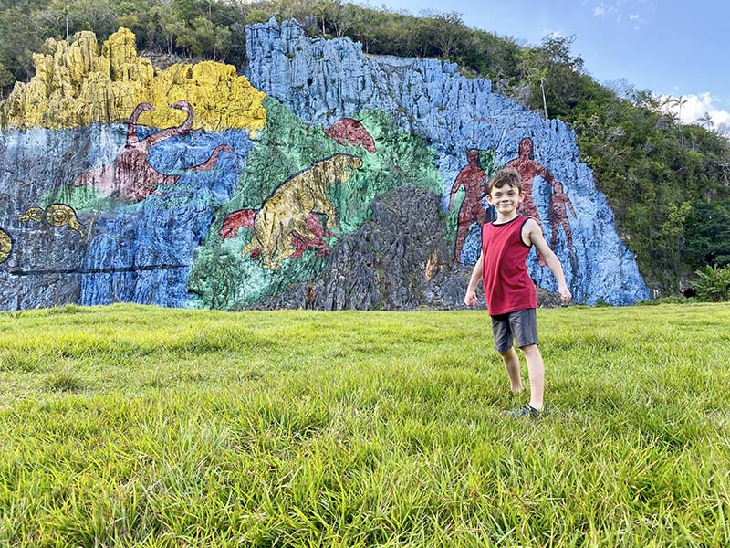Boy in front of Mural de la Prehistoria in Viñales