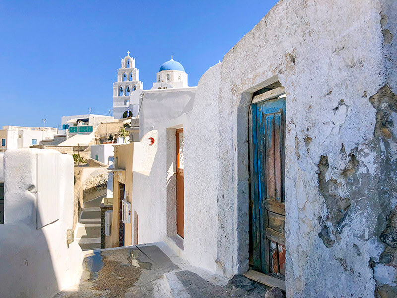 Alley view of church bell tower in Pyrgos, Santorini in Greece