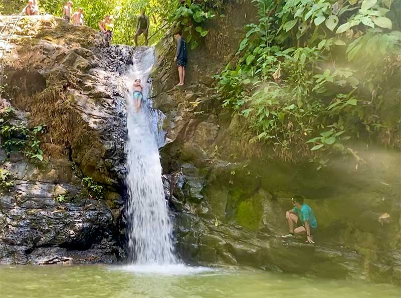 Boys sliding down the Uvita Waterfall